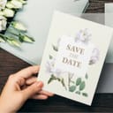 A woman holding a 'Save the Date' wedding invitation