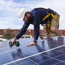 A handyman installing solar panels on a roof