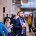 Hipster businessman with coffee cup at the train station