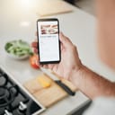 Phone screen, cooking recipe and man with healthy kitchen salad information on website, digital blog or vegan food app. Hand with smartphone, internet or online inspiration advice for green lifestyle
