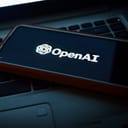 OpenAI icon displayed on smartphone lying on laptop keyboard