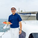 portrait of a smiling male waiter on a luxury catamaran serving fresh fruit to passengers