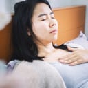 woman in bed struggling with heartburn and difficulty breathing due to acid reflux