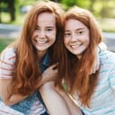 Smiling twin sisters hugging outdoors