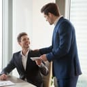 A manager giving a piece of paper to a smiling employee