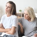 two women sitting in their living room with elderly mother scolding her adult daughter