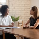 Smiling businesswoman discussing and negotiating with a female job candidate during an office meeting