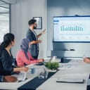 A man giving a presentation to his coworkers by showing a graph on a TV