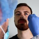 Health worker taking a swab sample from inside a man's nostril