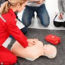 Woman demonstrating CPR on mannequin in first aid class