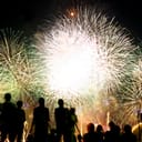 Silhouettes of people watching large fireworks