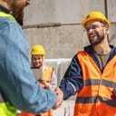 close-up of two construction workers shaking hands at a construction site