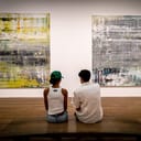 A man and woman sitting on a bench admiring abstract artwork at a museum