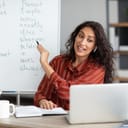 Joyful female teacher giving an online English class, pointing to basic grammar rules on a whiteboard