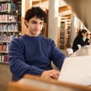 student working on diploma project and researching online in a modern library