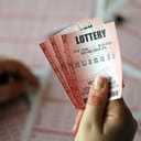 holding three lotto tickets in hand