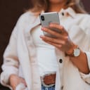 woman in white coat holding silver iphone 6
