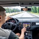 Man touching screen of a GPS navigation system in his car.