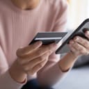 Close up female hands holding credit card and smartphone, young woman paying online, using banking service, entering information, shopping, ordering in internet store, doing secure payment