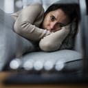 A sad woman laying on a sofa