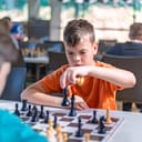 A focused school kid engaged in a chess game at a tournament.