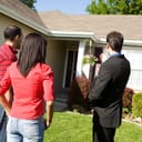 A male real estate agent presenting a property to prospective homebuyers.