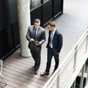 Two businessmen walking and talking while looking at a tablet