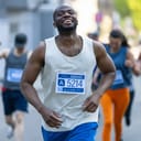 young man running during a city marathon, smiling as he approaches the finish line