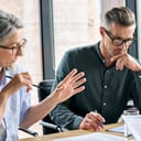 two mature people having a discussion over a project in a modern office setting