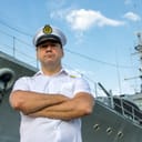 Sailor standing in front of a navy ship