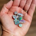 Close-up of rough opal nobbies on the person's palm, sourced from the renowned mining town of Lightning Ridge, Australia.