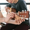 man showing woman how to play a simple guitar chord