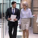 Two coworkers walking in the hallway of an office and talking