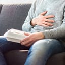 a man who ate too much is holding his stomach with his hand