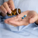 An elderly person taking medicine from a medicine bottle