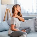 Pain in the shoulder. Upper arm pain, People with body-muscles problem, Healthcare And Medicine concept. Attractive woman sitting on the bed and holding painful shoulder with another hand.