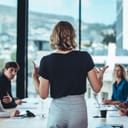 back view of a woman talking to her colleagues during a boardroom meeting at the office