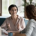 mature businesswoman speaking to a younger female colleague at an office table