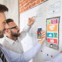Two men working on a UI design using a white board and a phone