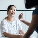 A mature woman with a confused look on her face looking at a person who is talking to her