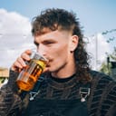 Man with a mullet hairstyle enjoying a beer on a sunny day