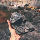 Man holding a large coal nugget at a mining site