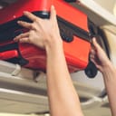 A person placing their carry-on luggage in an overhead compartment