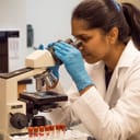 Female lab technician looking through a microscope