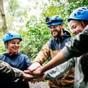 Smiling group of people wearing protective gear bringing their hands together
