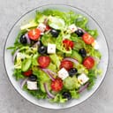 top view of a vegetable salad with cucumber, tomato, olives, onion, lettuce, and feta cheese