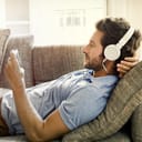 A young man listening music using his headphones while resting on a couch