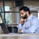 A focused bearded man working on his laptop in an office