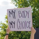 a woman holding 'My Body My Choice' sign at an abortion rights rally