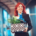 A happy woman carrying a box with her belongings